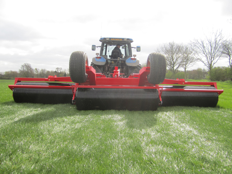 Rear view of 6.3m HE-VA hydraulic-folding Grass Rolls behind a New Holland tractor