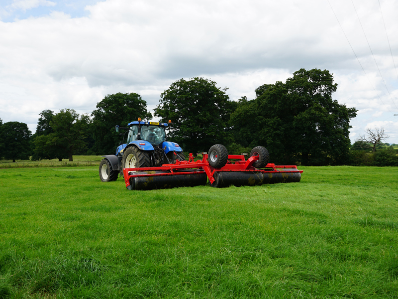 8.2m HE-VA hydraulic-folding Grass Rolls working in field with trees in background